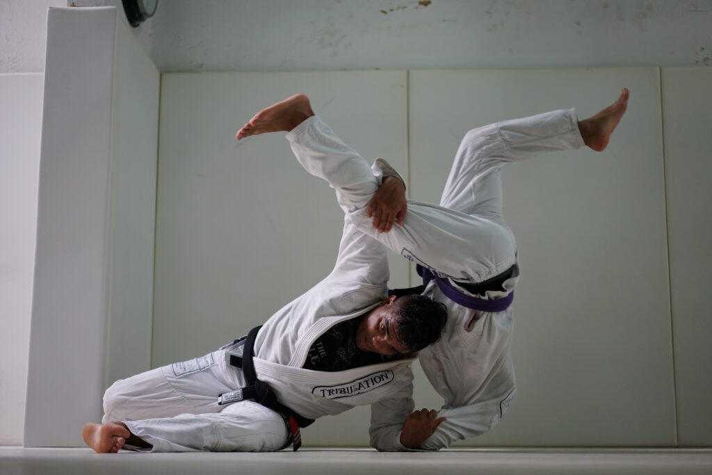 Male BJJ instructor performing throw